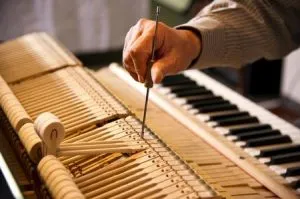 Bob Weller, professional piano tuner, adjusting piano strings with specialized tuning tools